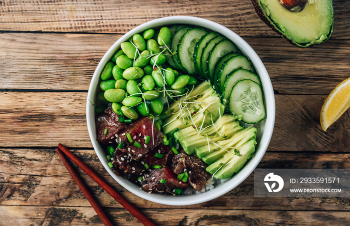 Poke bowl with raw tuna, rice, avocado, edamame beans and cucumber in a bowl. Hawaiian ahi poke bowl