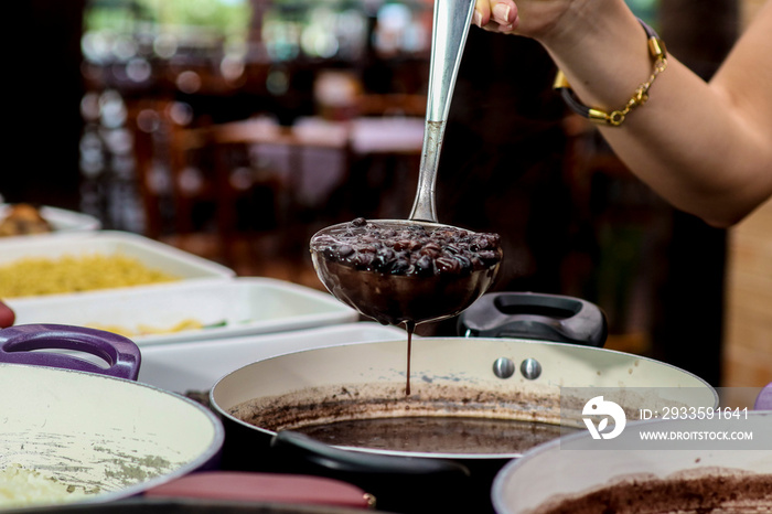 hand holding spoon with brazilian feijoada.