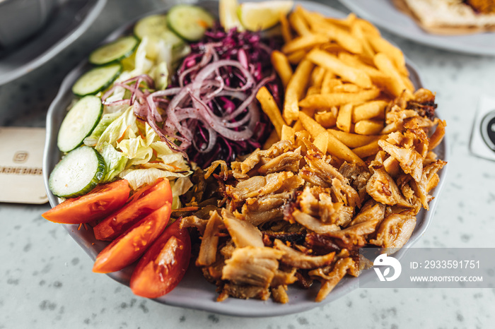 Doner Kebab on plate with vegetables fries and souce, grilled meat on plate