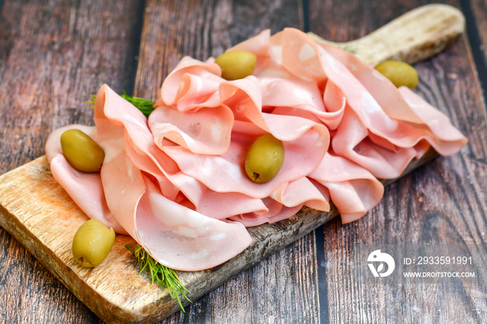 Slices Of  Traditional Italian antipasti mortadella Bolognese  on a wooden  cutting board