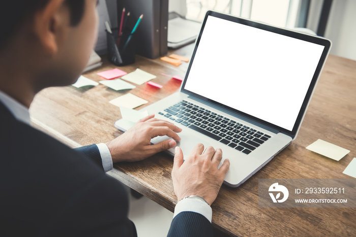 Businessman working on laptop computer with empty white screen at his desk