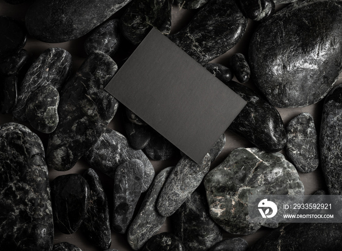 black mock up business card on black stones or galet ,concept of zen spa or sauna branding .