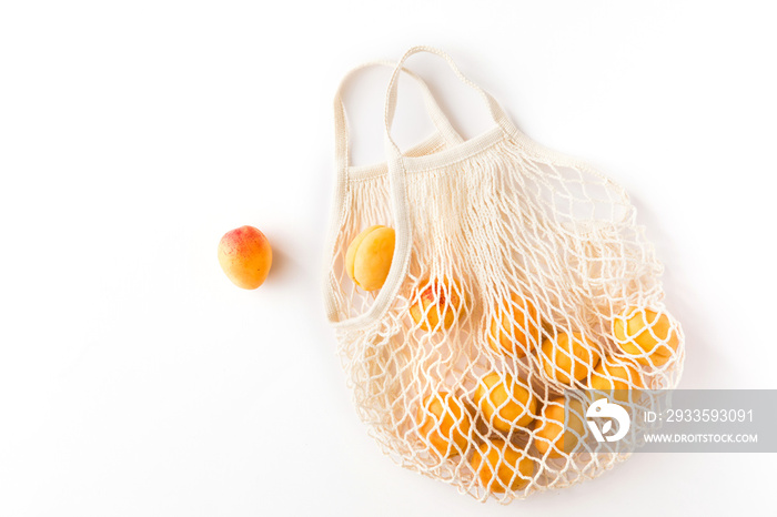 Top view of mesh shopping bag with organic eco fruits isolated on white background. Caring for the environment and the rejection of plastic concept