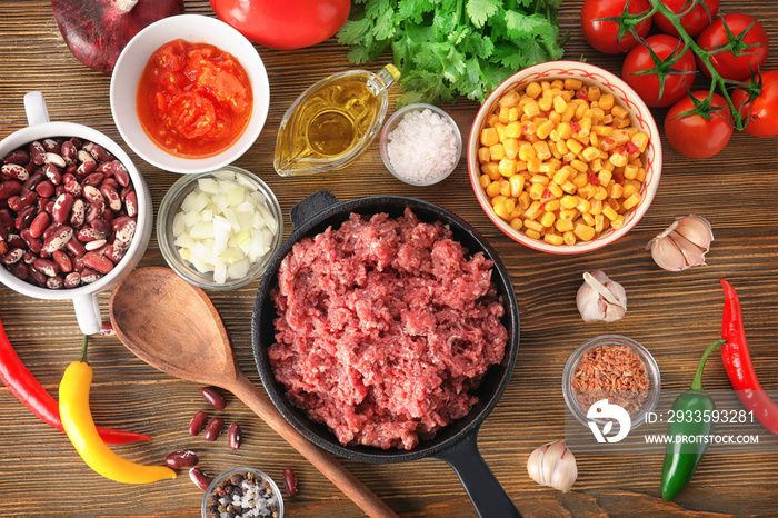 Composition with raw minced meat and chili con carne ingredients on wooden background