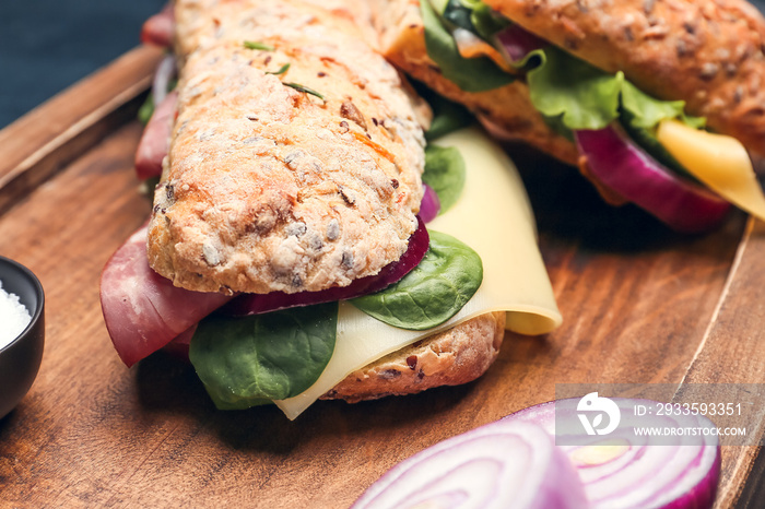 Board with tasty ciabatta sandwiches on wooden background