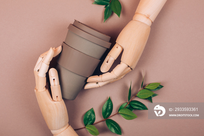 Wooden hand holding reusable cup of coffee. Concept of plastic-free and zero waste living