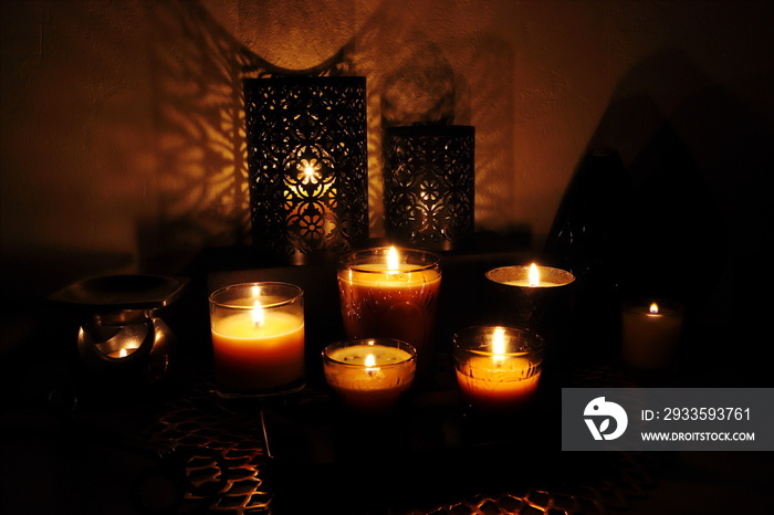 Many glass of scented aromatic candles are lighting in the dark living room