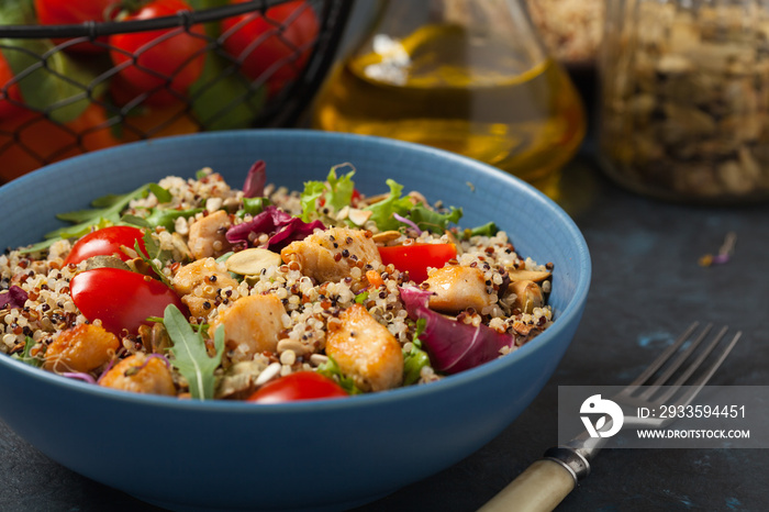 Salad with quinoa, avocado and chicken. Front view. Served in a blue bowl.