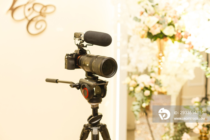 Professional photo camera on black tripod. White background. Shooting wedding ceremony. Photographer equipment