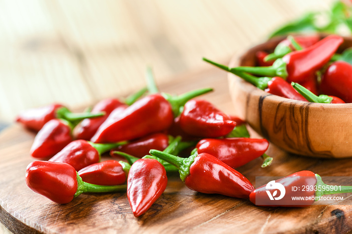 Red hot peppers in old wooden bowl side view. Chili spicy pepper on table copy space.