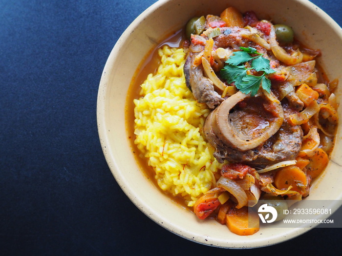 Italian Osso Buco alla Milanese : veal shank stew and safran risotto, dark background, space for text