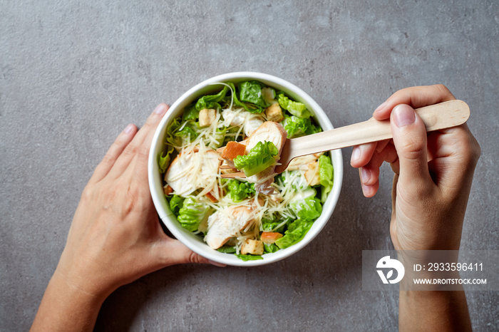 Eating Caesar salad from take away bowl; from above