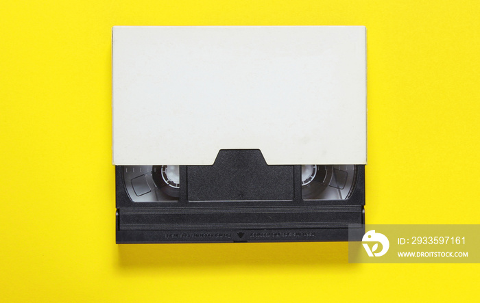 The videotape in a paper case on on yellow background. Pop culture attributes, minimalism. Top view