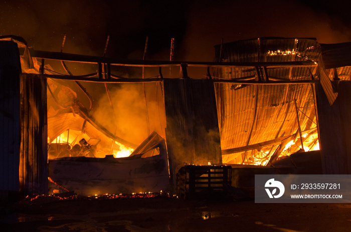 a garage on fire with flames coming thought the roof