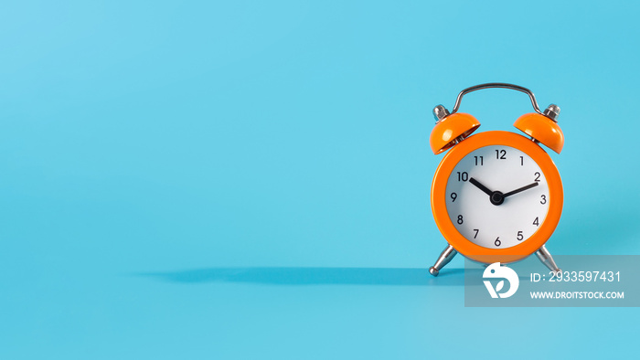 Top view photo of classic little orange alarm clock isolated over light color blue backdrop.