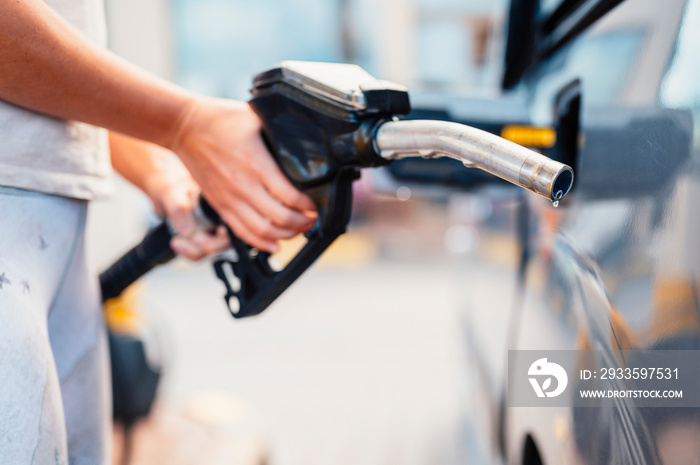 Closeup of woman pumping gasoline fuel in car at gas station. Petrol or gasoline being pumped into a motor. Transport concept