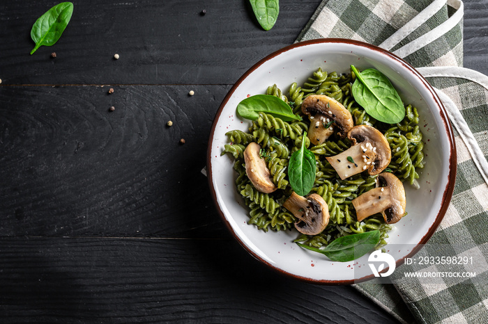 Mushroom and Spinach Pasta in a Bowl, Vegan Food on dark background. Vegan or gluten free diet. banner, menu recipe place for text, top view