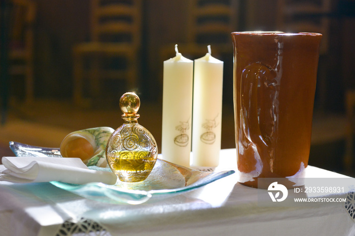 Éléments préparés sur une table pour la cérémonie d’un baptême dans une église, éclairés par le soleil en contre-jour