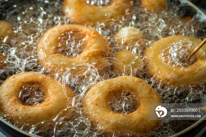 Frying donuts on hot oil. Homemade pastries for Fat Thursday.