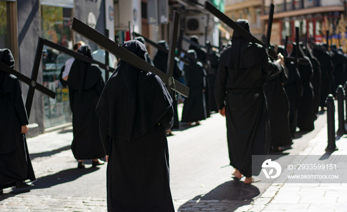 Barefoot penitents walk in procession with the cross