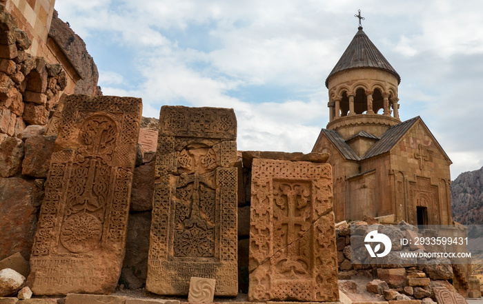 Ancient khachkars, stone crosses and with the Surb Astvatsatsin Church on background at the territory of the Noravank Monastery, Armenia