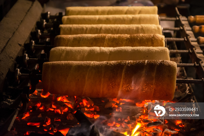 Preparation of the Hungarian traditional kurtos kalacs roasted over charcoal in Christmas market. A Hungarian sweet specialty Kurtos Kalacs made in Budapest.