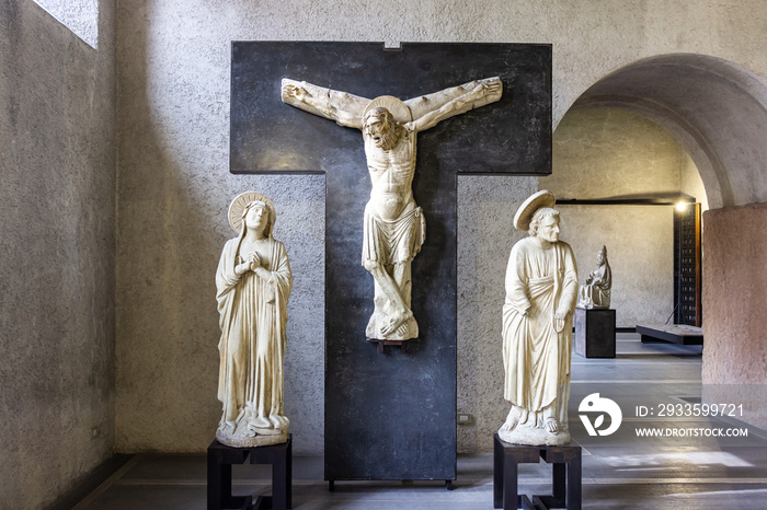 Stone statues of saints and a bas-relief with a crucifix at the exhibition in the Castelvecchio Museum of the Castelvecchio Castello Scaligero fortress in Verona, Italy.