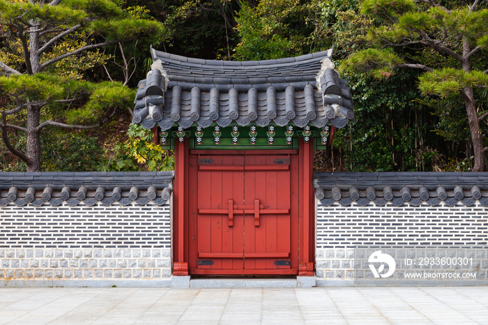 Red wooden gate under tiled roof. Traditional Oriental architecture