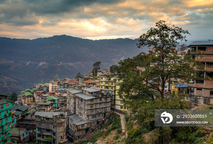 Sunset over himalayan city Gangtok, Sikkim, India with vibrant sky distant cliffs and buildings.