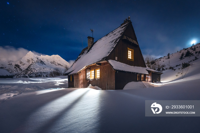 Mountain chalet in the Tatras during the blue hour. Winter mountain landscape with a view of the mountain ridges.