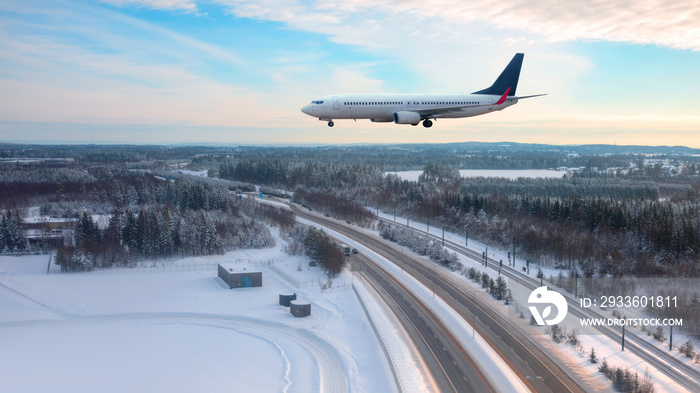 A passenger plane landing at Oslo Gardermoen International Airport - Airport in a snow covered - Beautiful winter landscape with aerial view of highway road and snow-covered road