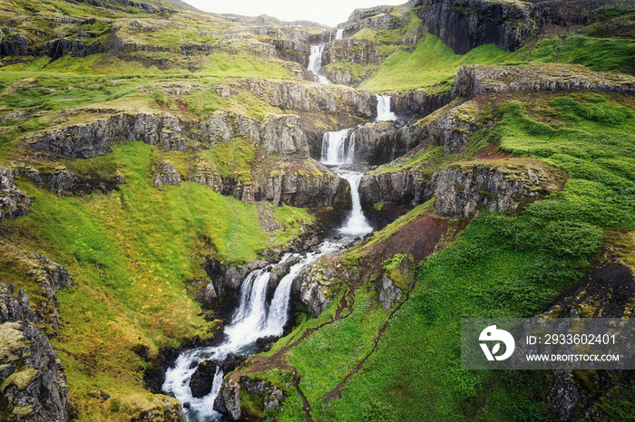 Klifbrekkufossar seven tier waterfall flowing hidden in the Mjoifjordur Fjord on summer at Iceland