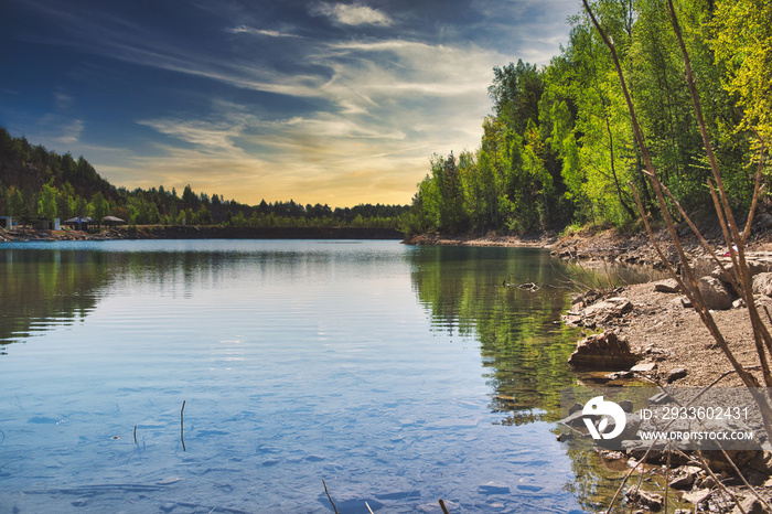 A lake with crystal clear water. The concept of rest by the lake, rest by the reservoir. Beautiful lake among trees, forest.