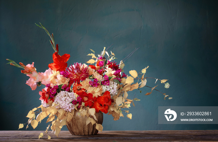 autumn bouquet with red and yellow flowers in ceramic vase on dark background