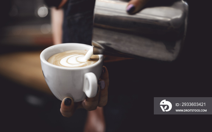 Coffee latte art, barista pouring milk into cup