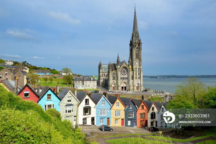 Colorful row houses with towering St. Colman’s Cathedral in background in the port town of Cobh, Ireland