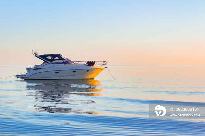 Photo of white colored motor boat drifting in evening sunset open sea.