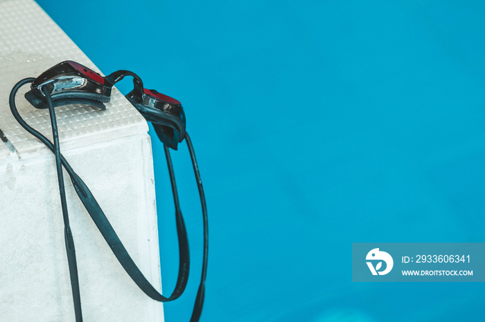 swimming goggles are on the parapet near the swimming pool. indoor swimming sports equipment