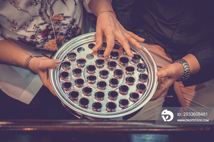 Taking holy Communion. Top view of glass in metal plate with red wine, bread in church, old hand take cup of red wine