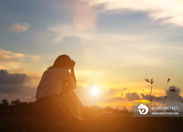 Silhouette of woman praying over beautiful sky background