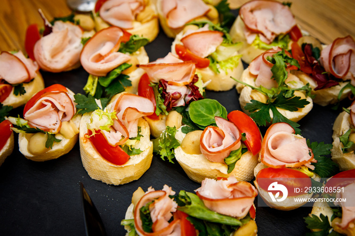 Set of beautiful small sandwiches on black stone plates. Buffet table.