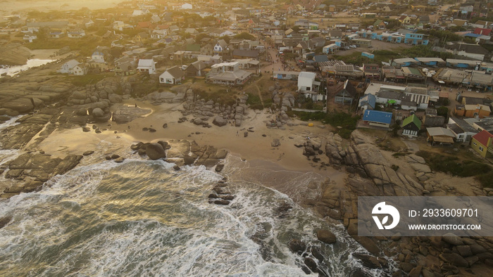 Waves crashing at sunset on rocks of Punta del diablo beach in Uruguay. Aerial top-down shot