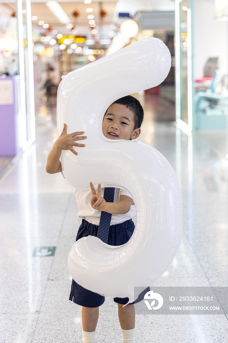 一个抱着充气字母气球的小男孩