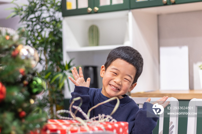 一个小男孩坐在圣诞礼盒前开心地张开双手