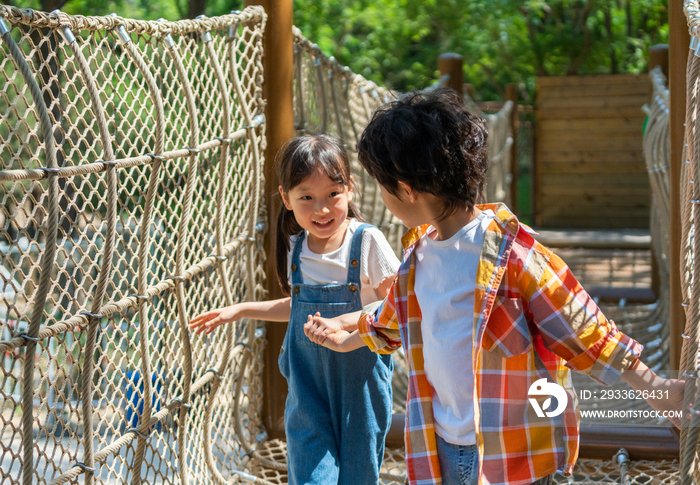 两个小孩子相互鼓励牵手走绳桥