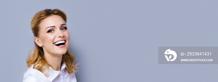 Very happy excited confident business woman with opened mouth over grey background with empty copy space area for some text. Caucasian blond laughing girl. Wide horizontal composition.