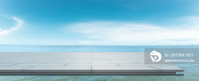 Clean square floor and lake water under blue sky.