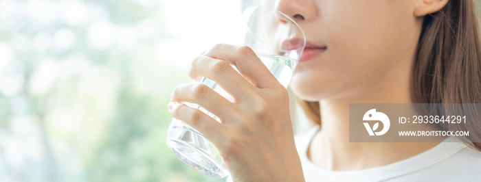 Happy beautiful, asian young woman, girl drinking, sip fresh glass of water for hydration of body, holding transparent glass in her hand, thirsty at home. Health care, healthy lifestyle concept.