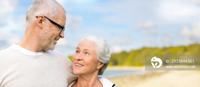 old age, retirement and people concept - happy senior couple hugging over beach background