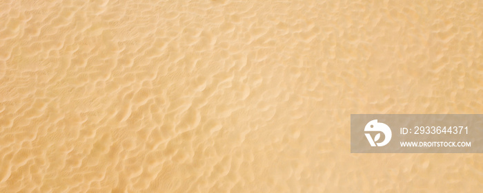 Top view on a pattern of clean beach sea sand. Panoramic background with texture.